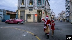 El actor cubano Yusuany Casneiro vestido como Santa Claus camina por una calle de La Habana. (AP/Ariel Ley)